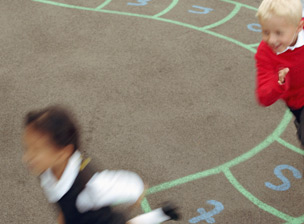 Three children (6-8) running in playground (blurred motion)