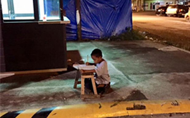 Little boy does his homework in McDonald’s lights