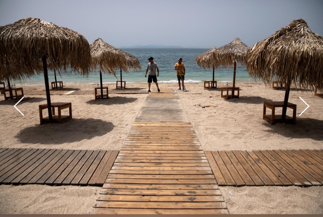 Greeks return to beaches in heatwave, but keep umbrellas apart